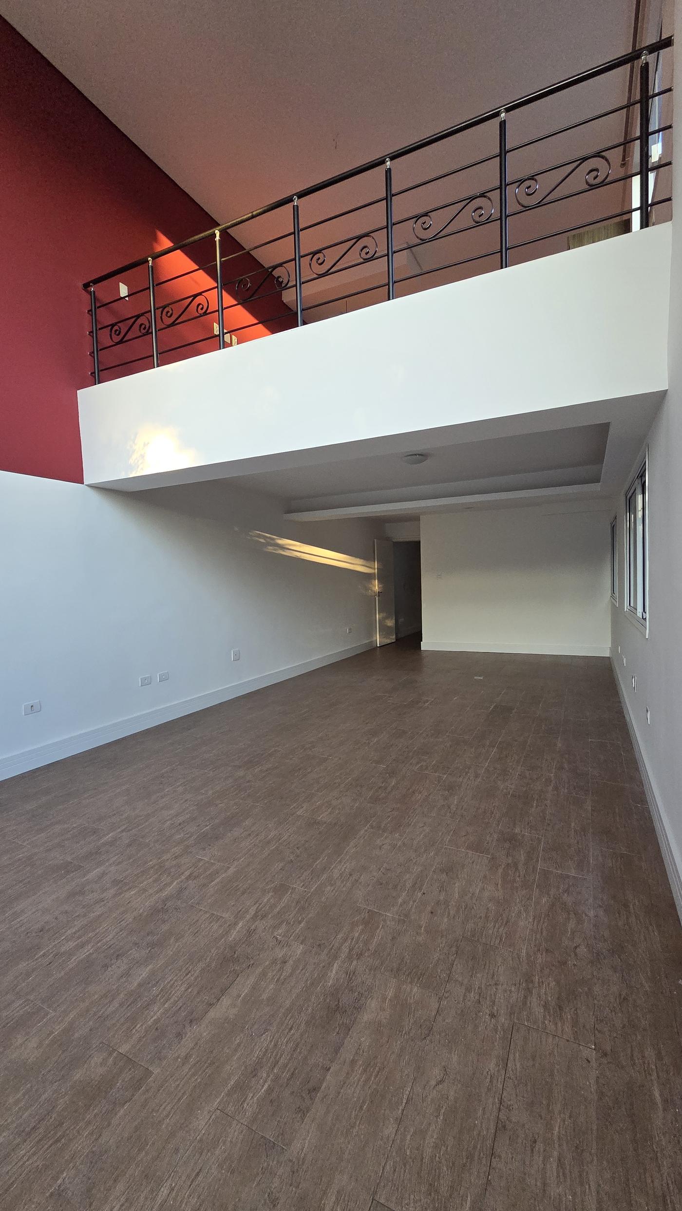 Sala de estar com pé-direito duplo e mezanino em ferro trabalhado
